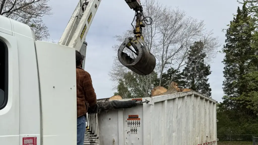 A large truck removes stumps from a site with new construction